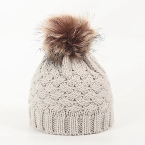 Detail of light grey knit baby beanie with large brown pompom and cable stitch texture