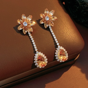 Macro shot of vintage champagne zircon flower earrings on textured brown leather background