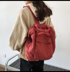 Rear view of a red canvas backpack for women featuring top handles and spacious design