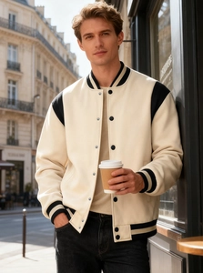 Outdoor street photo of a men's varsity jacket with cream body and black sleeves