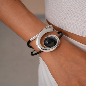 Detail of silver wavy metal bracelet with oval black stone on multi-strand black rope