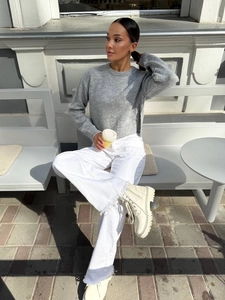 Women's grey crewneck sweater with side slit design paired with casual white trousers
