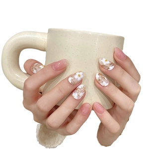 Faux ongles faits main rose tendre avec motifs floraux blancs et accents dorés
