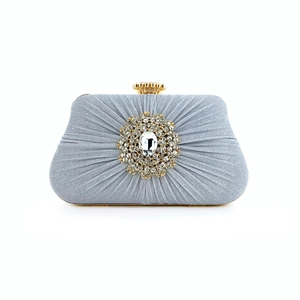 Detail of silver pleated evening bag featuring a crystal flower clasp and gold metal trim