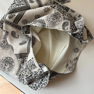 Detailed interior of a paisley canvas bag with a silver magnetic buckle and inner pocket