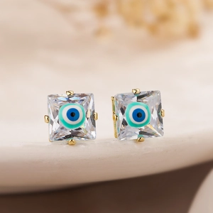 Detailed macro view of gold-plated square stud earrings with zircon and nazar evil eye