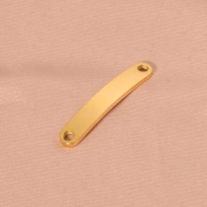 Close-up of golden curved metal connector with two holes for DIY jewelry making
