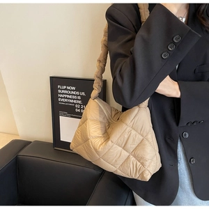 Detail of beige quilted puffer bag with textured rhombic stitching and soft strap