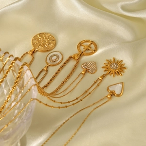 Detailed shot of golden necklaces with sun and heart pendants on elegant champagne silk