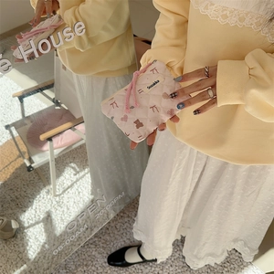 Close-up of quilted floral coin purse with bear pattern held by a model in soft light