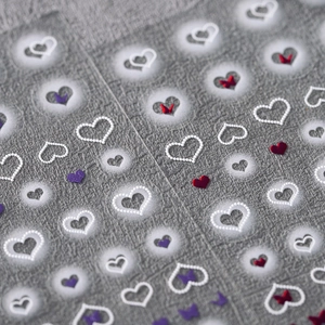 3D heart and butterfly nail art stickers with textured pearl finish on neutral fabric
