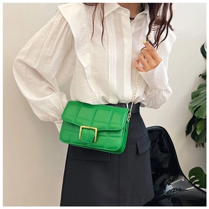 Detail of green quilted crossbody bag with golden square clasp and chain strap