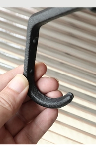 Close-up of black cast iron curved hook with vintage industrial texture and finish