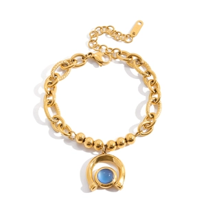 Detail of 18K gold-plated horseshoe bracelet featuring blue resin stone and mixed chain