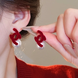 Detail of red velvet double C earrings with white pearl drop on a model ear