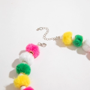 Gros plan détaillé des pompons colorés et du fermoir en métal sur le collier fantaisie