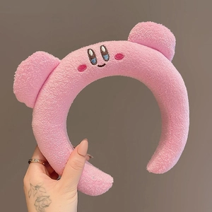 Close-up of pink plush headband featuring cute embroidered cartoon character face details