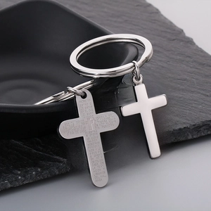 Stainless steel cross keychain with Spanish prayer engraving on black stone surface