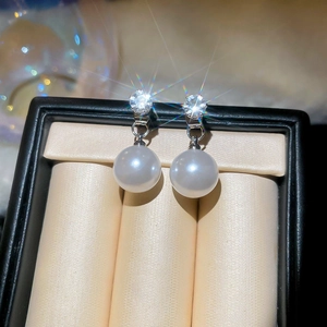 Macro detail of elegant silver earrings featuring sparkling cubic zirconia and white pearls