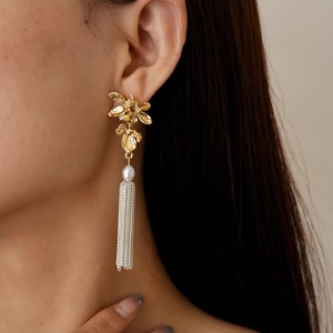 Gros plan de boucles d'oreilles fleurs avec perle blanche et longs pompons en chaîne