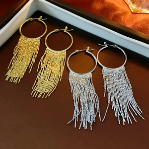 Detail of gold and silver hoop earrings with long metallic fringe tassels in a jewelry box