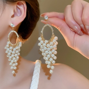 Macro shot of gold tassel earrings featuring pearl grape clusters and sparkling rhinestones