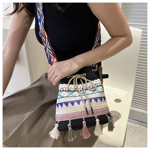 Detail of colorful ethnic embroidery and tassel decor on a black woven bucket bag