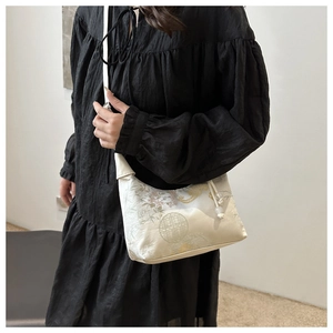 Detail of elegant vintage Chinese style embroidery handbag worn by model in black dress