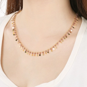 Golden necklace with pink-purple beads and drop pendant worn on neck