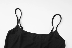 Gros plan d'un caraco noir à fines bretelles avec texture de tissu doux sur fond blanc