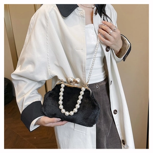 Detail of a black plush shell bag featuring a pearl handle and a golden metal clasp