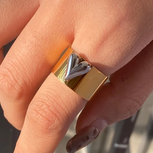 Wide gold stainless steel ring featuring a 3D silver heart, worn on a hand close-up