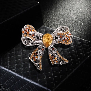 Luxurious silver bow brooch with amber rhinestones and teardrop gem on gift box