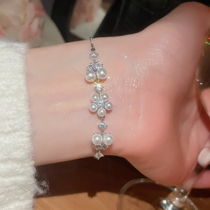 Close-up of a floral pearl bracelet with cubic zirconia on a wrist in elegant lighting