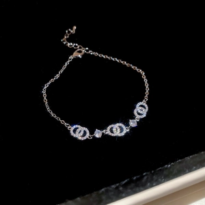 Makroaufnahme von Armband mit silbernen Ringen und funkelnden Zirkonia auf schwarzem Samt