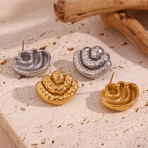 Macro shot of 18K gold and silver layered fan earrings with embossed dotted texture