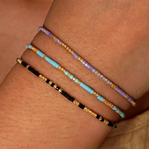 Three-piece set of thin beaded Morse code bracelets in purple, blue, and black gold tones