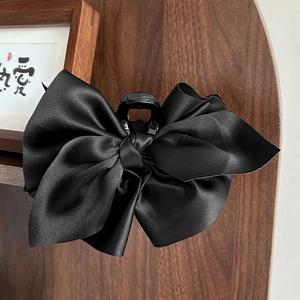 Detailaufnahme einer großen schwarzen Satin-Schleife Haarklammer auf Holzregal