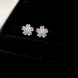 Detailed view of silver flower earrings with pink and white cubic zirconia on black velvet