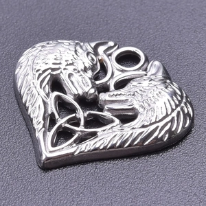 Macro shot of a stainless steel heart pendant with dual wolf heads and Celtic knot details