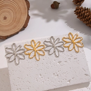 Hollow flower earrings in 18K gold and silver plating displayed on stone with pine cones