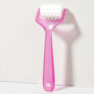 Detail of pink handheld scalp massager featuring a white textured rolling wheel