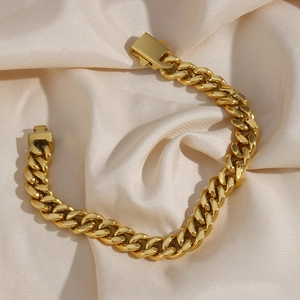 Trendy gold stainless steel Cuban chain bracelet with box clasp on beige silk background
