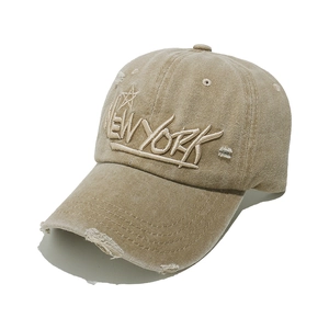 Detail of vintage khaki washed cotton baseball cap with New York embroidery and distressed brim