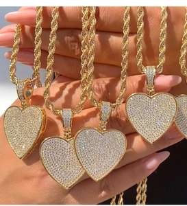 Detail of multiple iced-out gold heart pendants on thick rope chains with sparkling zircons