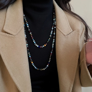 Close-up of bohemian colorful crystal beaded layers on a black turtleneck sweater