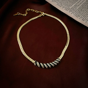 Détail du collier ras de cou doré avec émail noir et strass brillants sertis