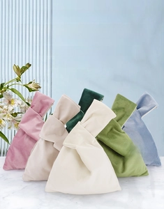Multiple colors of velvet wrist bags with soft fabric texture and minimalist handles