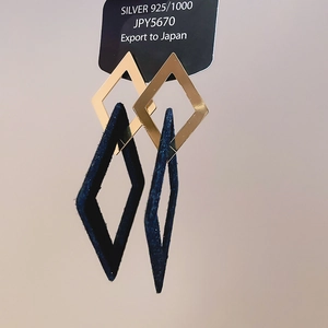 Detail of 925 silver earrings with golden metal and dark blue suede rhomboid pendants