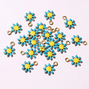 Macro detail of daisy flower pendants with blue enamel petals and golden steel loops